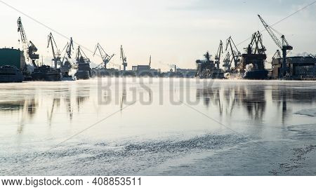 Cranes Of Of The Baltic Shipyard On A Frosty Winter Day, Steam Over The Neva River, Smooth Surface O