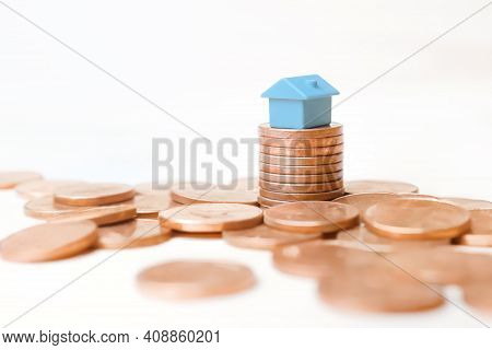 Blue Toy House Money Coins Stack On White Background. Mini House Model On Stack Coins Pile Money Hom