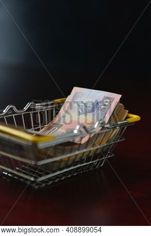 Ten Kuwaiti dinar currency notes in a shopping basket. Creative concept.