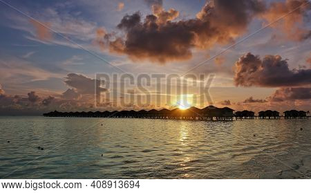 Fantastic Sunset In The Maldives. There Are Pink Clouds In The Blue Sky. The Sun Shines Gold On The 