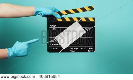 Hand Is Wear Blue Medical Gloves Pointing And Left Hand Hold Black Clapper Board Or Movie Slate With