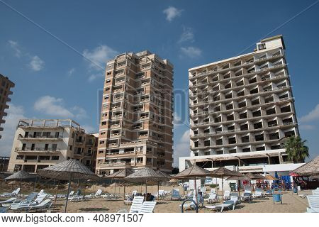 Famagusta, Cyprus - September 15 2016: Palm Beach With Beach Umbrellas And Tourists And The Abandone