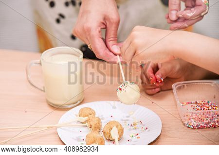 Mom And Child Together Themselves Cooking Of Cake-pops. The Mother Holds The Popcake On A Stick, The