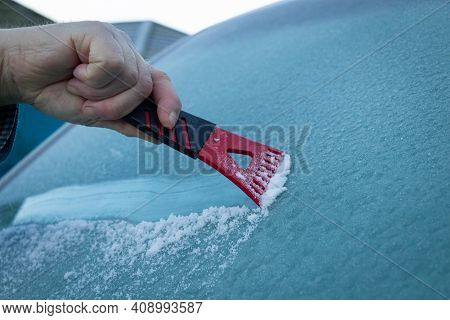 A Man Scraping Ice Off A Frozen Wind Shield Or Screen Of A Vehicle On A Cold Winters Morning