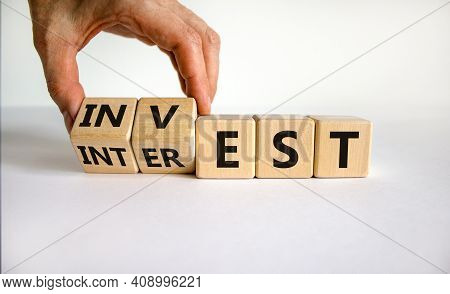 Invest Or Interest Symbol. Businessman Turns Wooden Cubes And Changes The Word 'invest' To 'interest