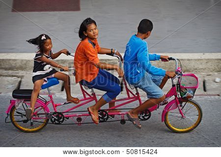 Three Childred On Tandem Bicycle On A Road