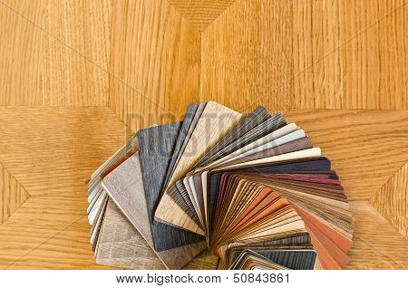 Different color samples of wood floor on brown parquet background.