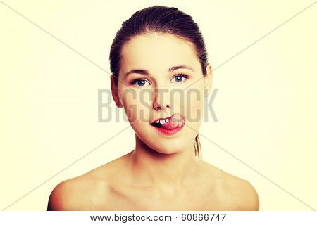 Front view portrait of a young beautiful female caucasian teen, having naked arms, makig a face with her tongue