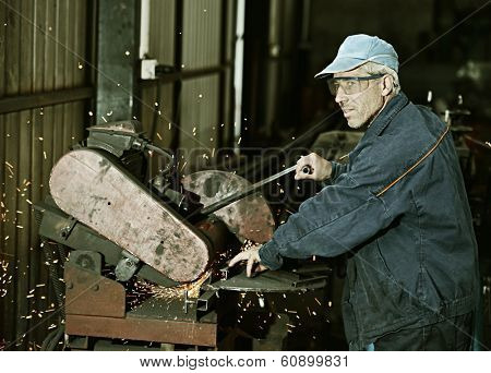 Industrial worker cutting and welding metal with many sharp sparks