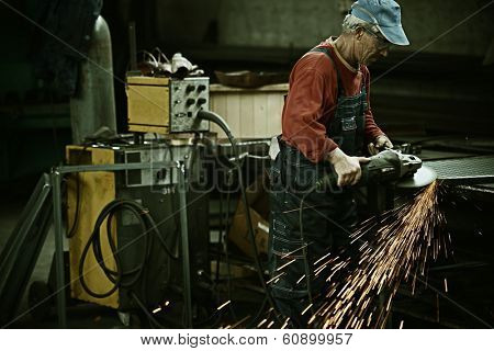 Industrial worker cutting and welding metal with many sharp sparks