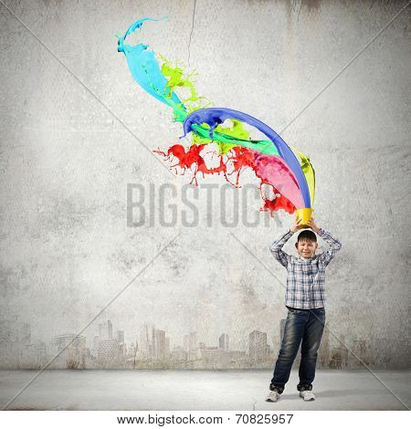 Young boy splashing colorful paint from bucket