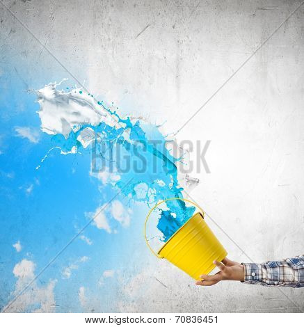Close up of hand splashing colorful paint from bucket