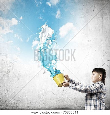 Young boy splashing colorful paint from bucket