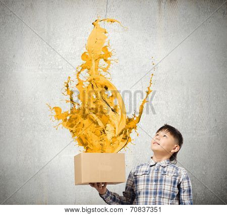 Young boy splashing colorful paint from carton box