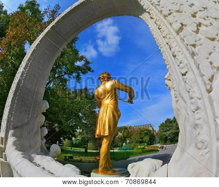 VIENNA, AUSTRIA - SEPTEMBER 27, 2013: Elegant gilded statue of Johann Strauss, playing the violin in white marble arch. Park in Vienna