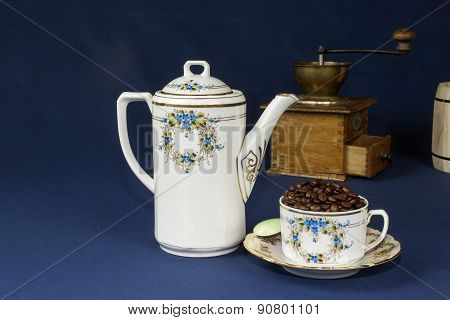coffee mug on the table with a blue tablecloth, poured out coffee beans