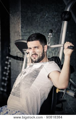 Man using pull down machine in gymnasium.Handsome muscular man exercising on pull down machine
