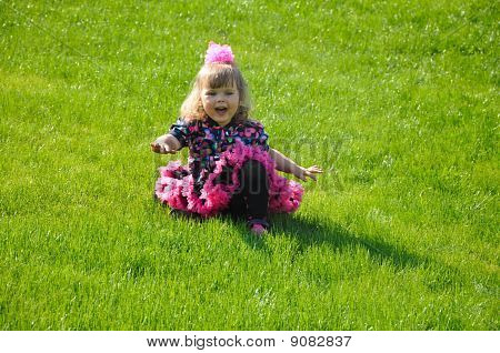 Menina feliz sentado no gramado verde