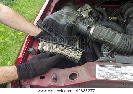 A Mechanic Replacing A Dirty Air Filter In A Truck