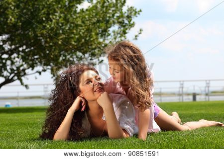 Young mother and daughter laying on the grass