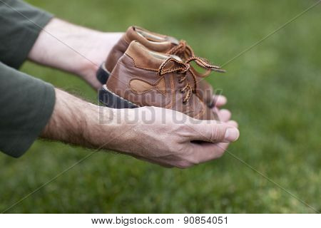 Dirty hands holding a pair of old childrens shoes
