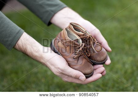 Dirty hands holding a pair of old childrens shoes