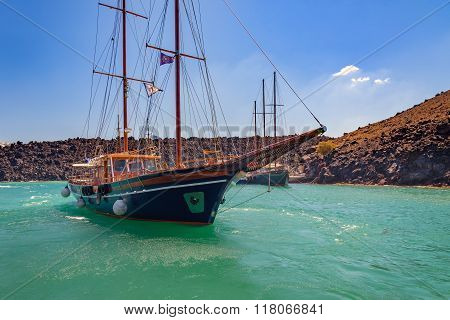 Wooden sailing boat at volcano bay near Santorini island, Greece