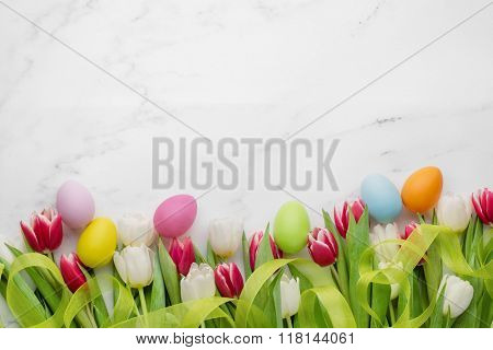 Easter eggs and tulips on white marble