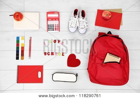 School set with backpack, shoes and supplies on light wooden background