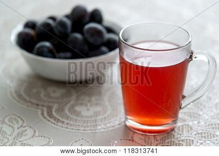 A cup of plum compote and frozen plums on the table