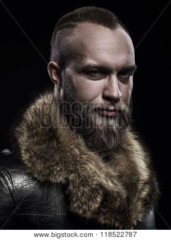 Brutal Handsome Glum Unshaven Man With Long Beard And Moustache In Black Fur Coat With Collar.