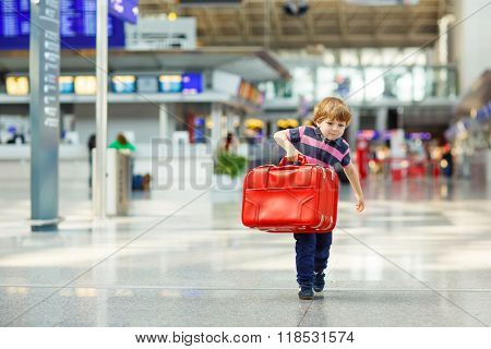 Cute little tired kid boy at the airport traveling. Upset child waiting with big suitcase. Canceled flight due to pilot strike.