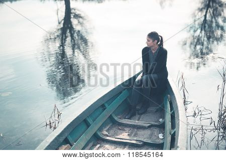 Girl at the old fishing boat looking to the lake.Melancholia sadness sorrow concept