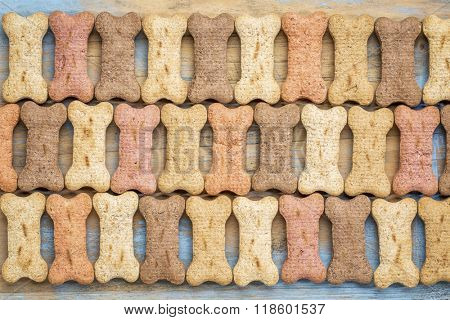 rows of milk bones (dog treats) in a variety of flavors - background on wood