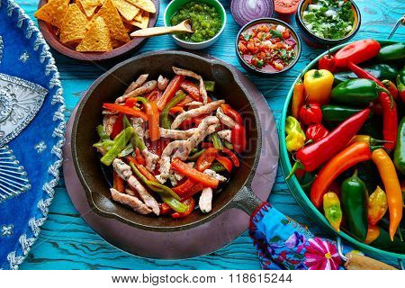 chicken fajitas in a pan with sauces chili and sides Mexican food