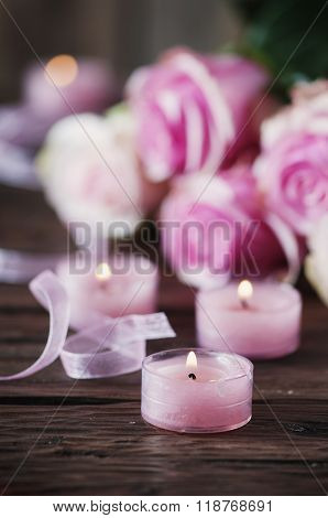 Pink Roses And Pinl Candles On The Wooden Table