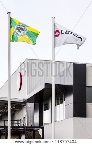 Vila Nova de Famalicao, Portugal. March, 2013: The flags of Leica and the Vila Nova de Famalicao city floating on the new cameras factory of the iconic Leica manufacturer. Inaugurated in March 2013.