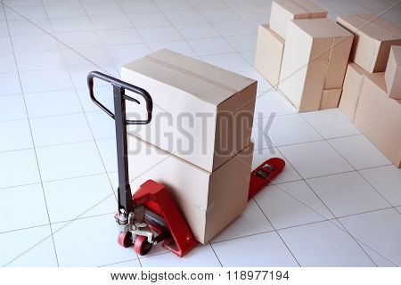 Fork pallet truck with stack of cardboard boxes indoors