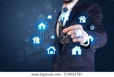 Businessman in suit holding keys with house graphics around and dark background