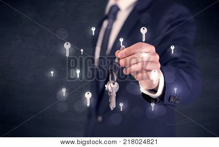 Businessman in suit holding keys with keys graphics around and dark background