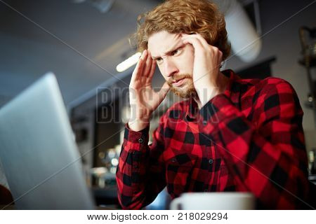 Young businessman concentrating on work while looking at laptop display