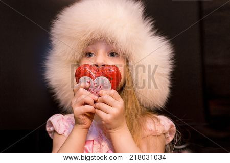 girl with heart. cute little girl in a fur hat holds the heart of love. Valentine's Day