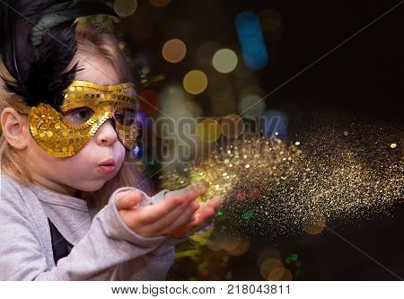 girl blowing golden dust. shine and lights of the night in a carnival mask