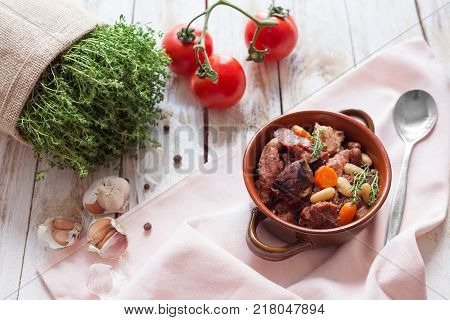 Cassoulet. Containing meat pork sausages goose duck and sometimes mutton and two types of white beans. French food (cuisine). On old wooden white background.