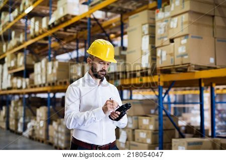 Warehouse worker or supervisor with barcode scanner. A mobile handheld PC with barcode scanner.