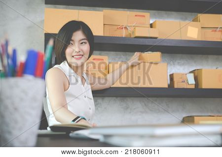 Charming beautiful asian teenager owner business woman work at home for online shoppingwriting the order and preparing package product with office equipment entrepreneur life style concept