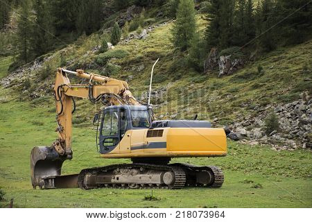 Excavator loader or backhoe machinery during earthmoving works outdoors at construction site in otztal alps mountain of Schnals city in Bolzano Austria