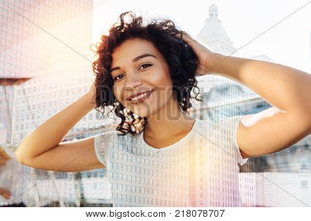 Unexpected moment. Happy cheerful young woman placing hands behind the head while grinning and resting