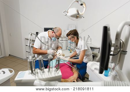 Process Of Preparing And Installing Dental Ceramic Crown. Male Professional Dentist And Female Assis