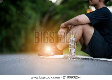 Young tired man having a rest after jogging outdoors summer time. Healthy lifestyle concept